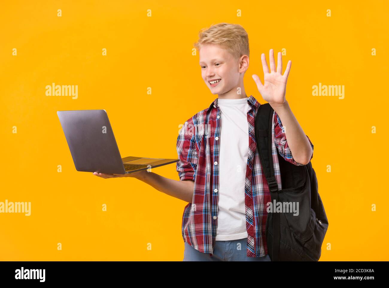 Happy boy using laptop for video call and waving Stock Photo - Alamy