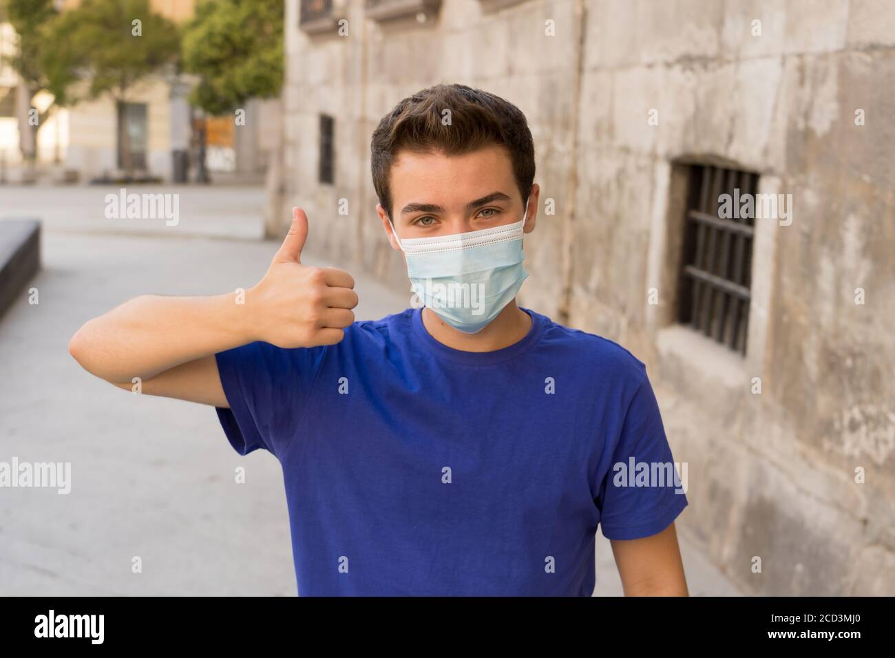 Happy young man with surgical face mask outdoors showing thumbs up. Man ...