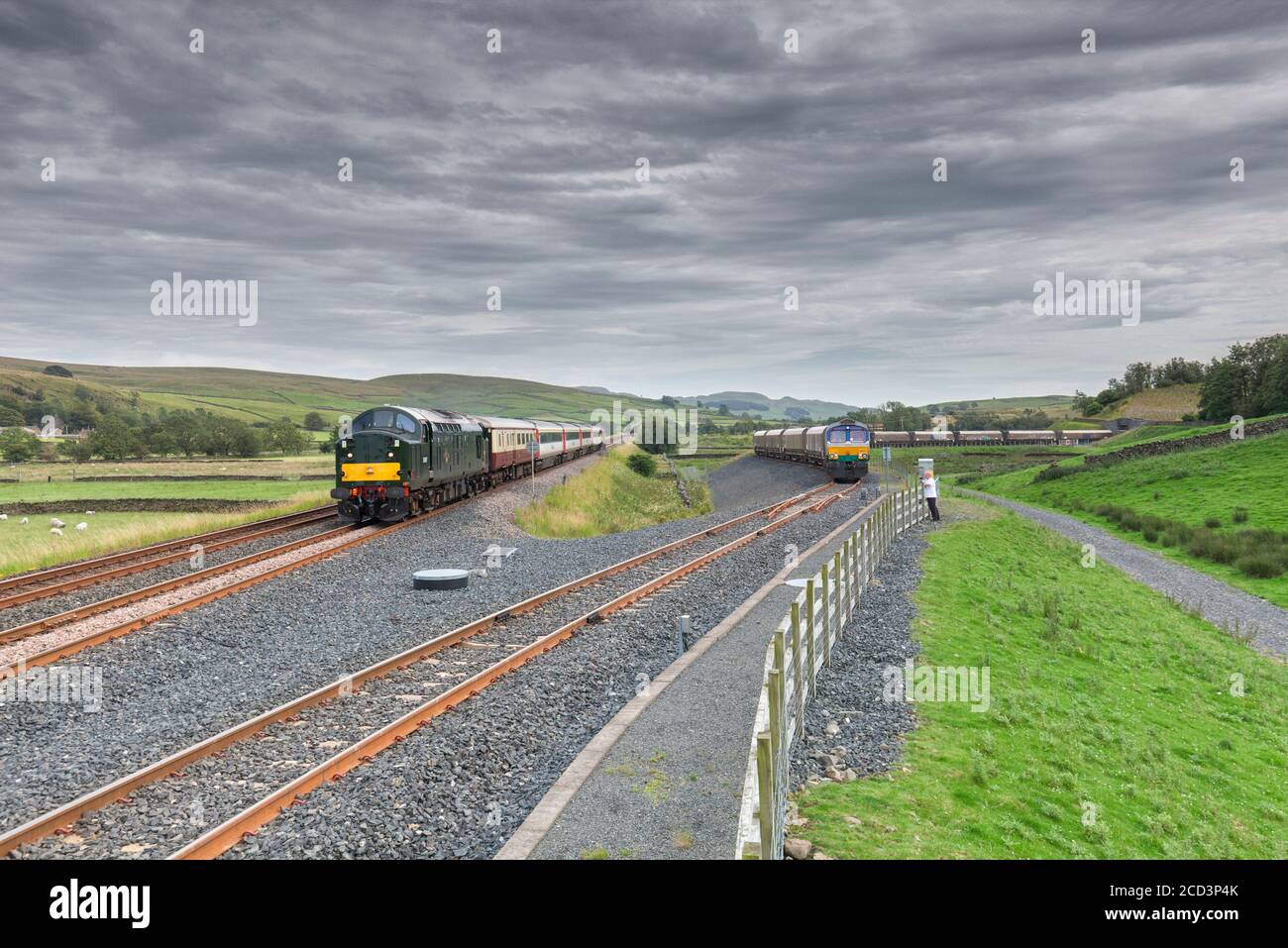 Class 37 locomotive 37521 passing  GB Railfreight class 66 66711 in the Arcow Quarry siding while hauling the 'staycation express' tourist train Stock Photo