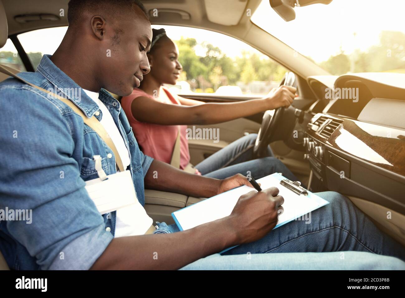 Male instructor examining black woman driving car Stock Photo