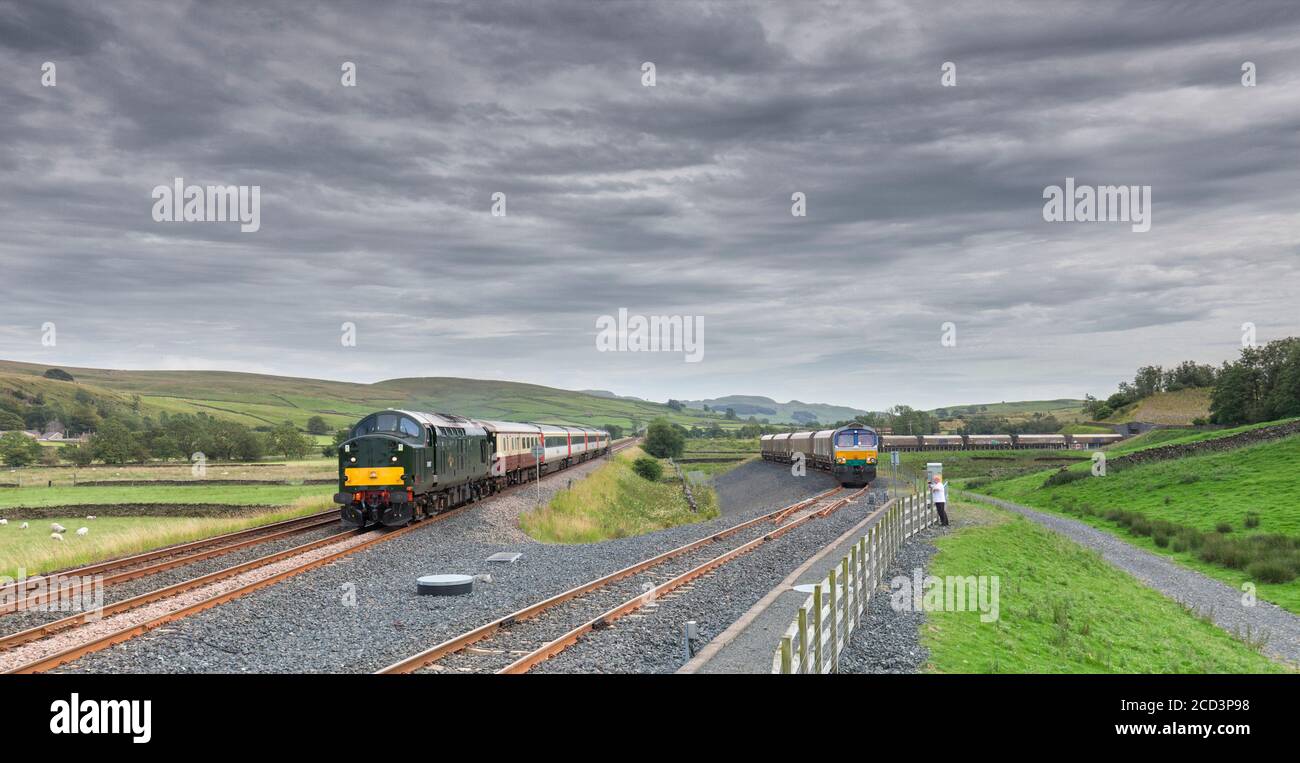 Class 37 locomotive 37521 passing  GB Railfreight class 66 66711 in the Arcow Quarry siding while hauling the 'staycation express' tourist train Stock Photo