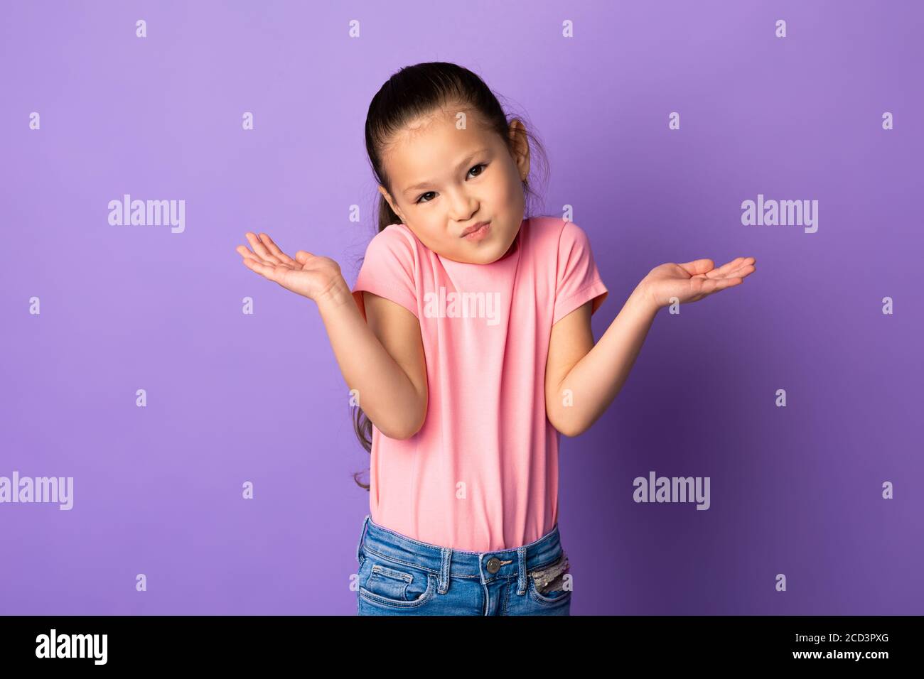 Confused puzzled asian kid shrugging at studio Stock Photo