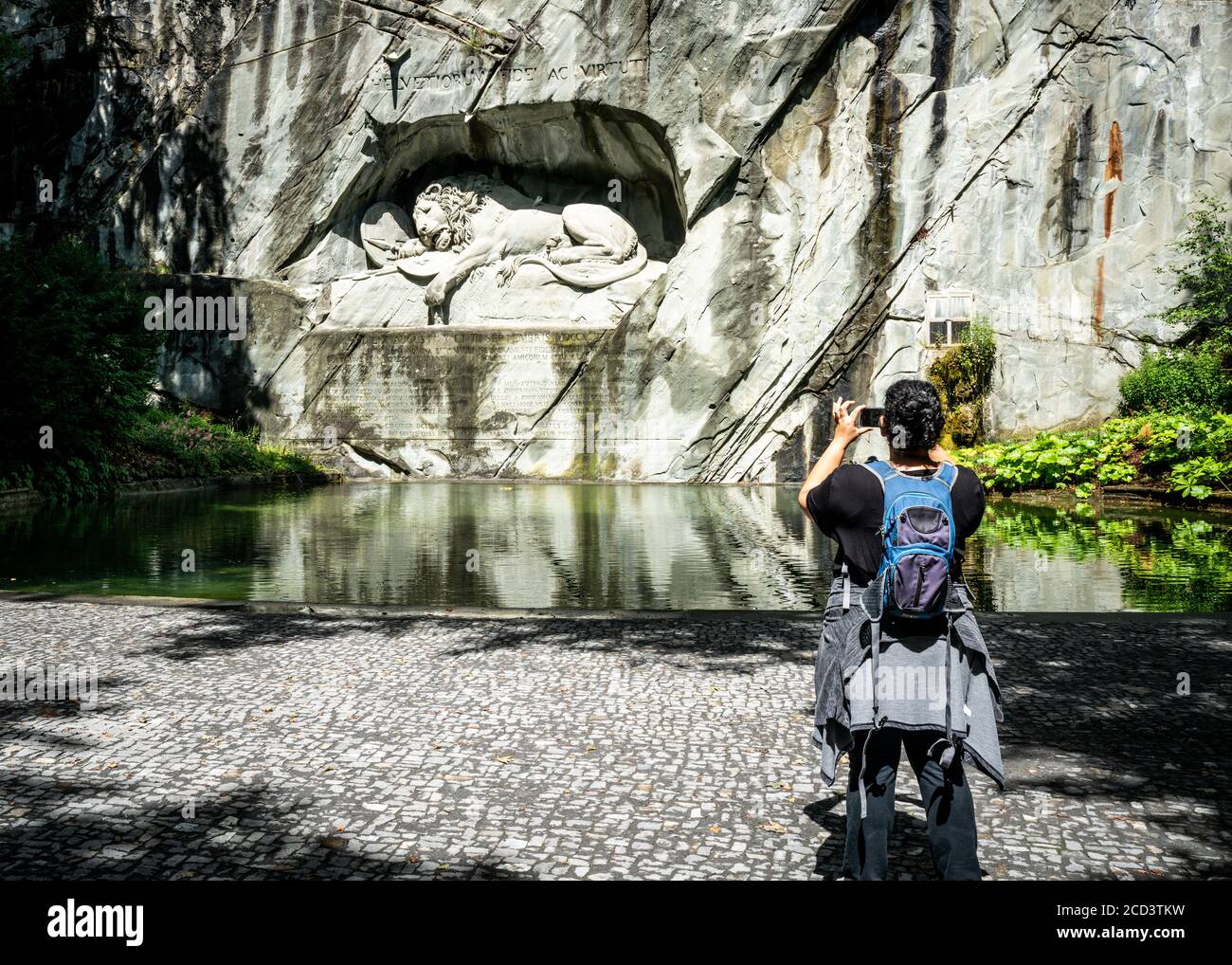 Unrecognizable tourist taking picture with his phone of the Lucerne Lion monument carving symbol of Lucerne city Switzerland ( translation : To the lo Stock Photo
