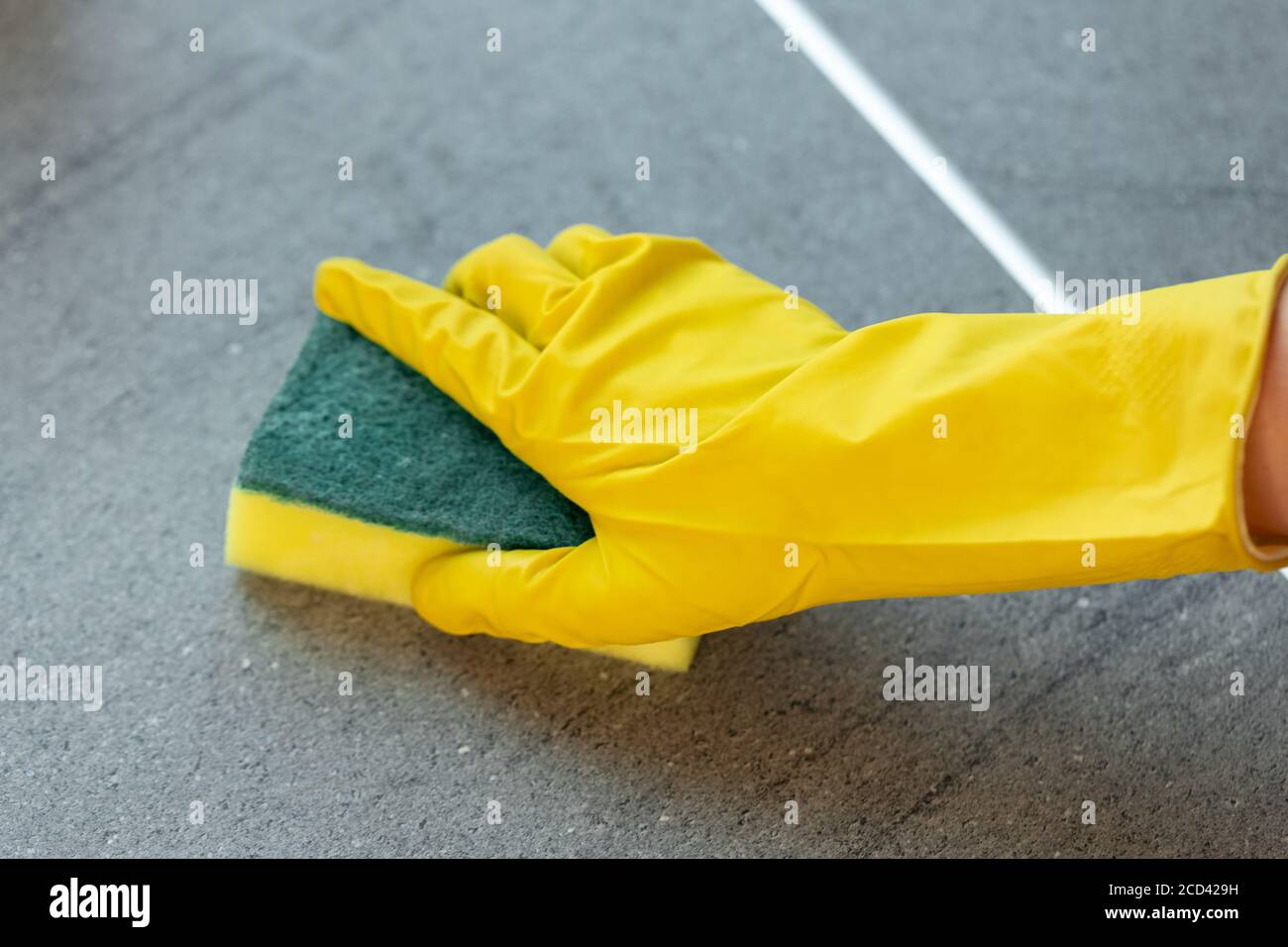 Woman's hands in yellow gloves cleaning counter top in kitchen Stock