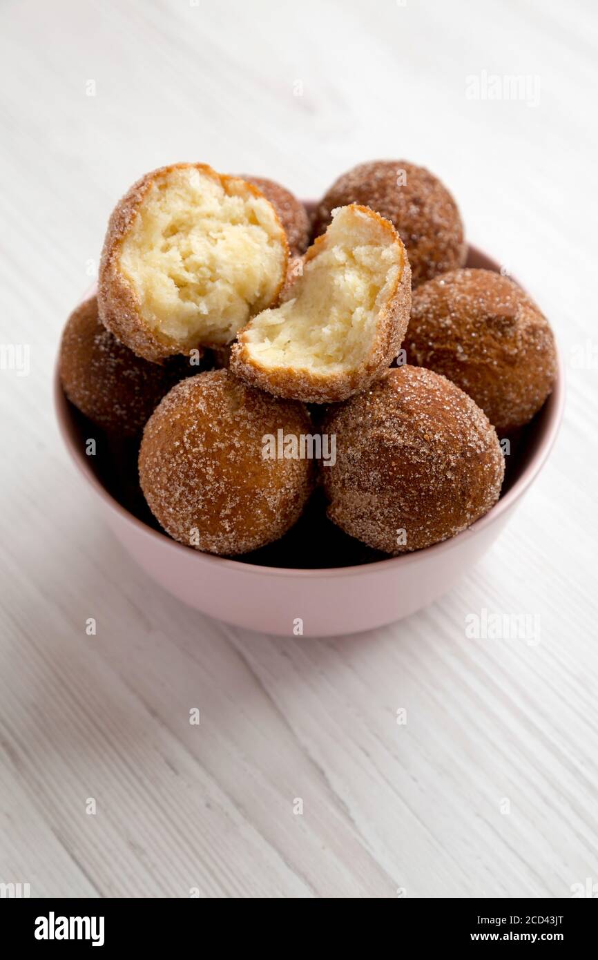 Homemade Fried Donut Holes in a pink bowl on a white wooden background, side view. Stock Photo