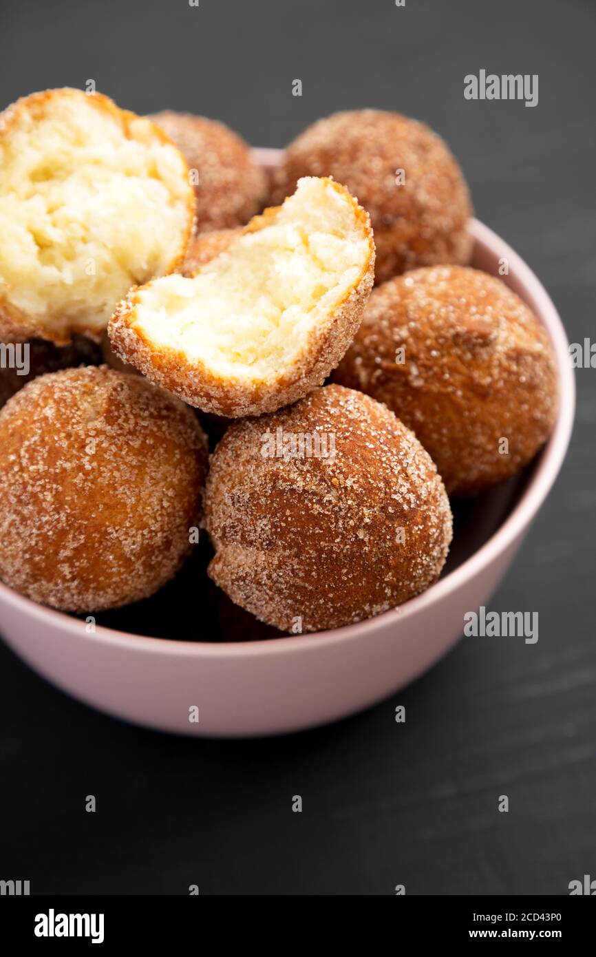 Homemade Fried Donut Holes in a pink bowl on a black background, side view. Stock Photo