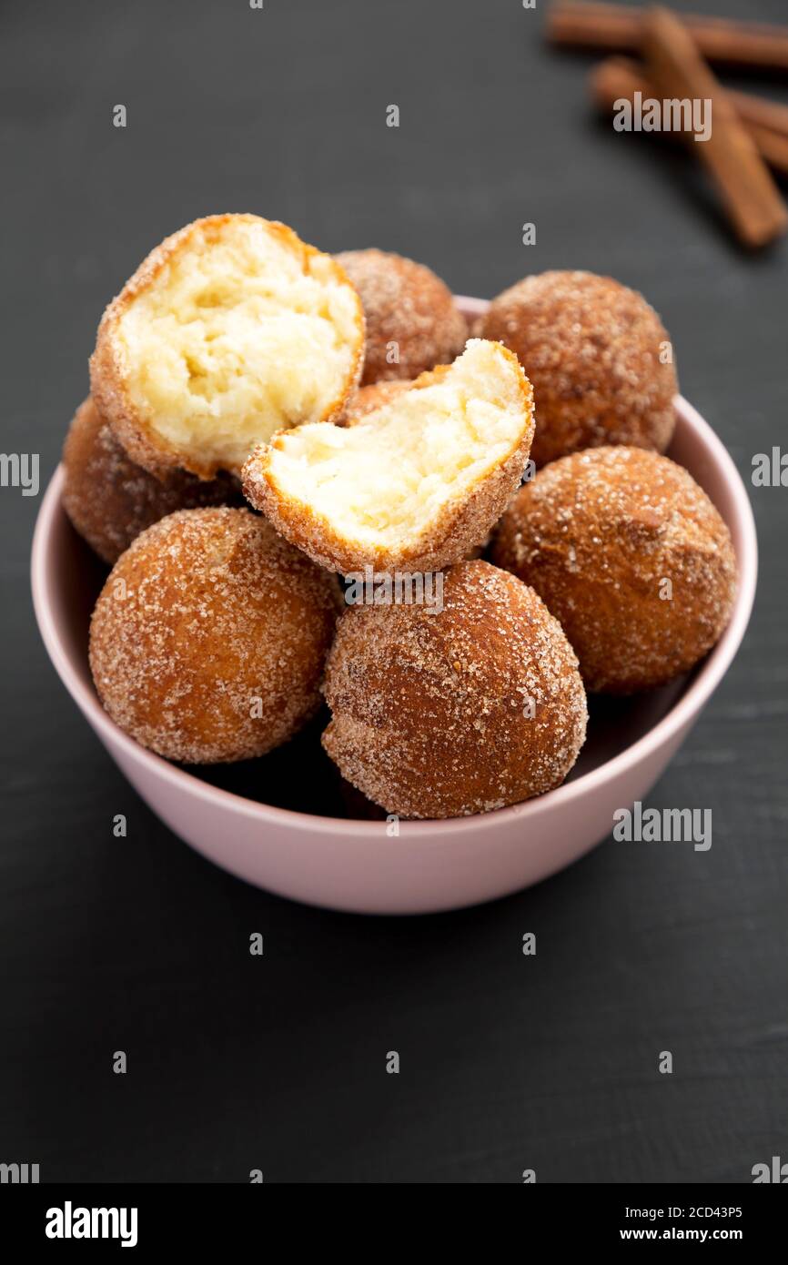 Homemade Fried Donut Holes in a pink bowl on a black background, side view. Stock Photo