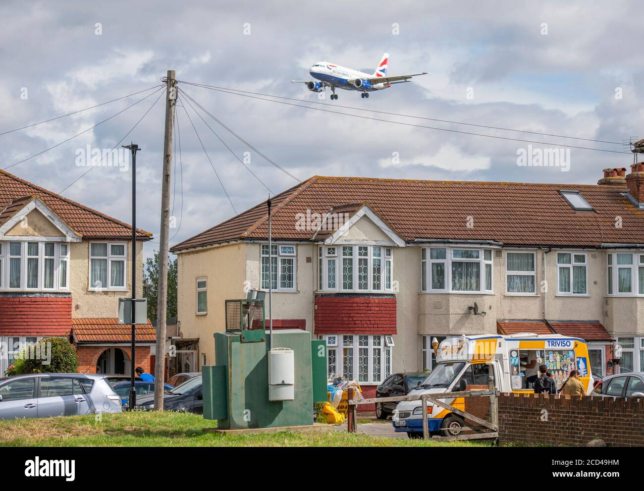 Heathrow Airport, London, UK. 26 August 2020. British Airways flight over Myrtle Avenue on approach to runway 27L at Heathrow in gusting wind, the remnants of Storm Francis. In foreground, an ice cream van visits the avenue. Credit: Malcolm Park/Alamy Live News. Stock Photo