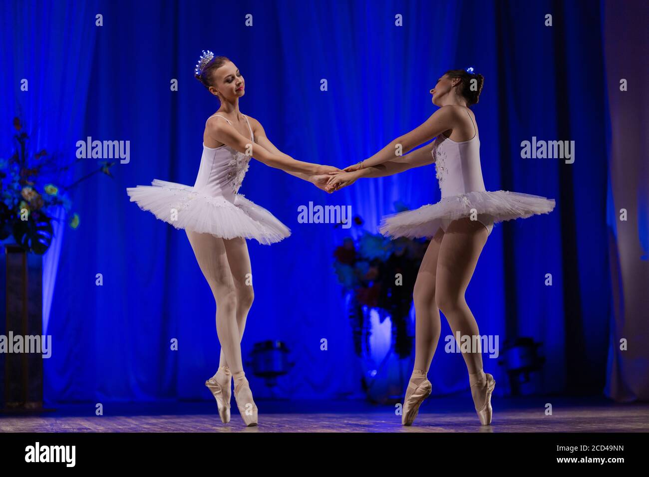 Young woman ballerina in a white tutu dancing performance on stage in a  theater on a blue background Stock Photo - Alamy
