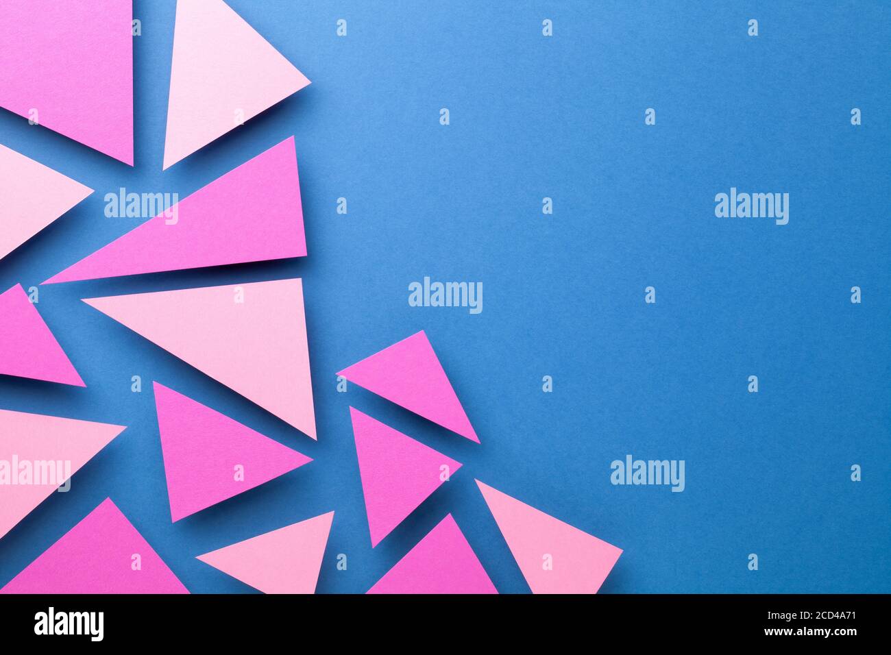 Pink triangular shapes in minimal creative style. Paper composition on blue background for presentations. Top view. Copy space Stock Photo