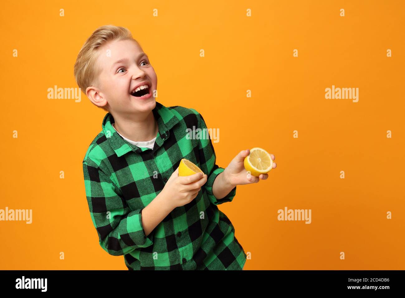 Sour face, cheerful facial expression. The boy bites a lemon. Happy child, facial expressions, energy and fun. Expression and joy of the child. The bo Stock Photo