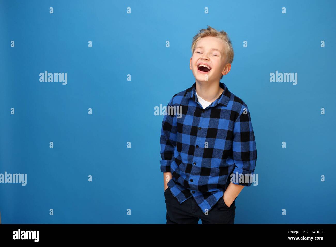 Smiling boy, happy child. Happy child, laughing boy. Happy, smiling boy on a blue background expresses emotions through gestures. Stock Photo