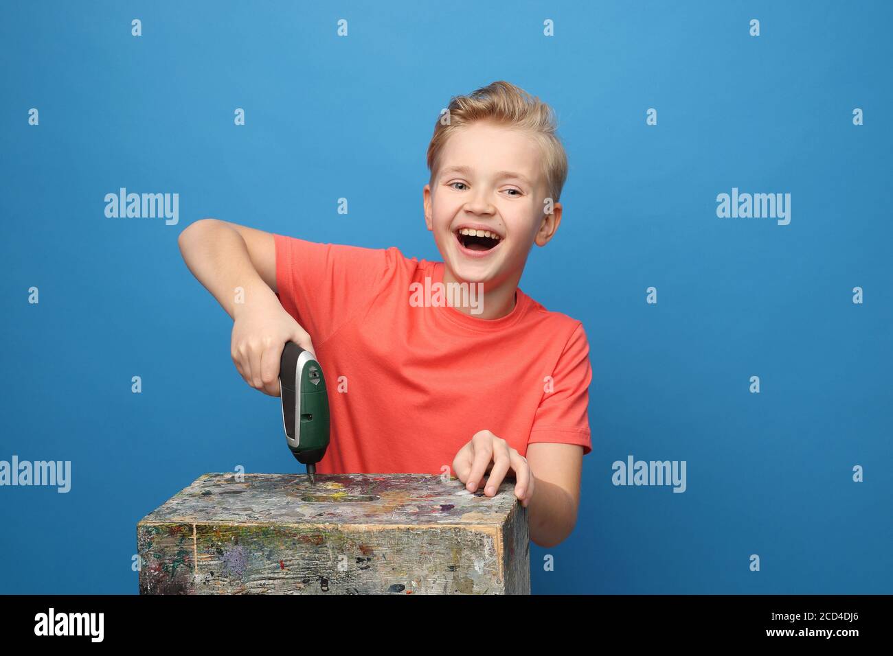 Child joy, play with DIY tools. The child plays with a screwdriver. Portrait of a boy on a blue background. Stock Photo