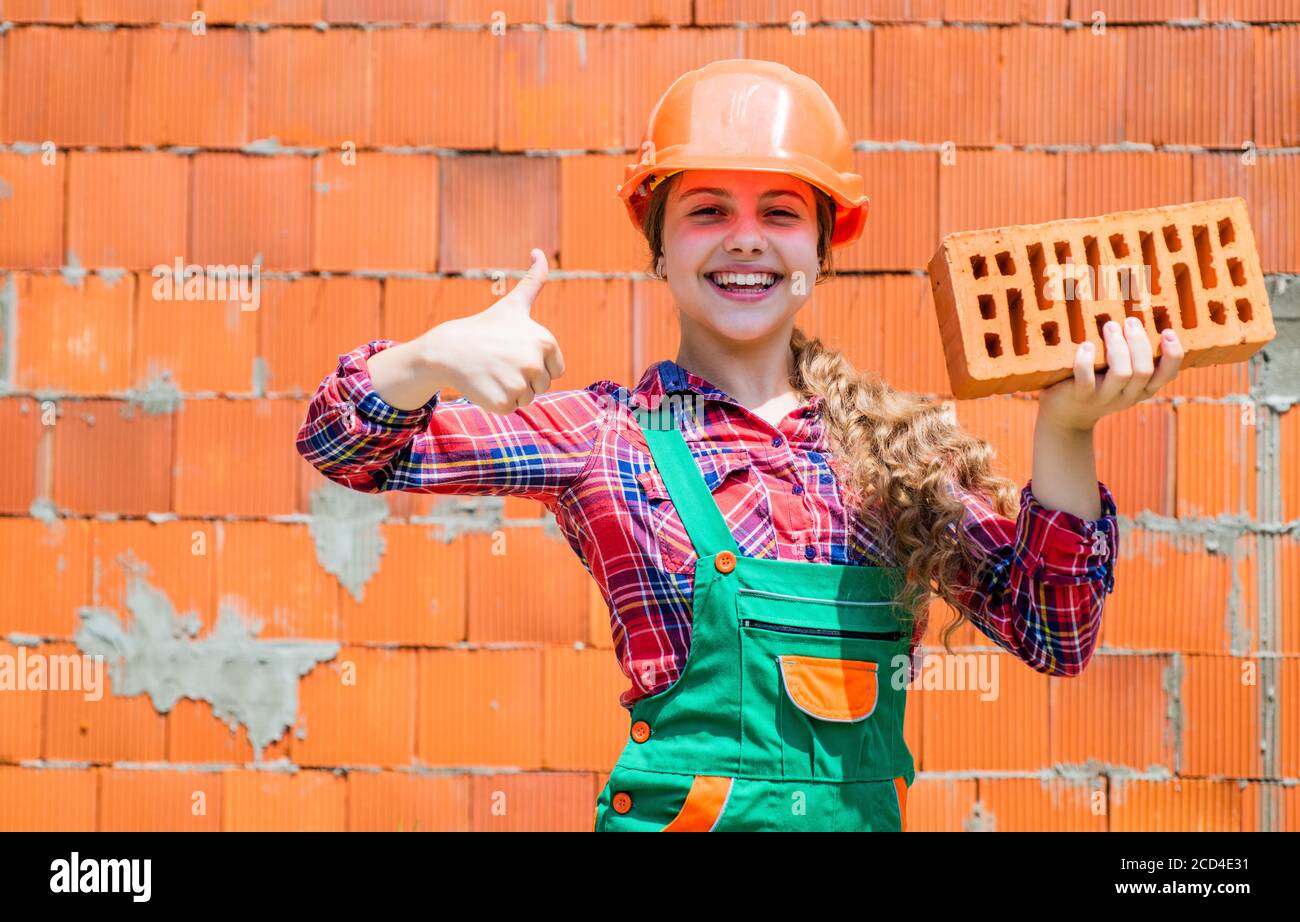 Little worker in helmet building from brick. Architecture construction