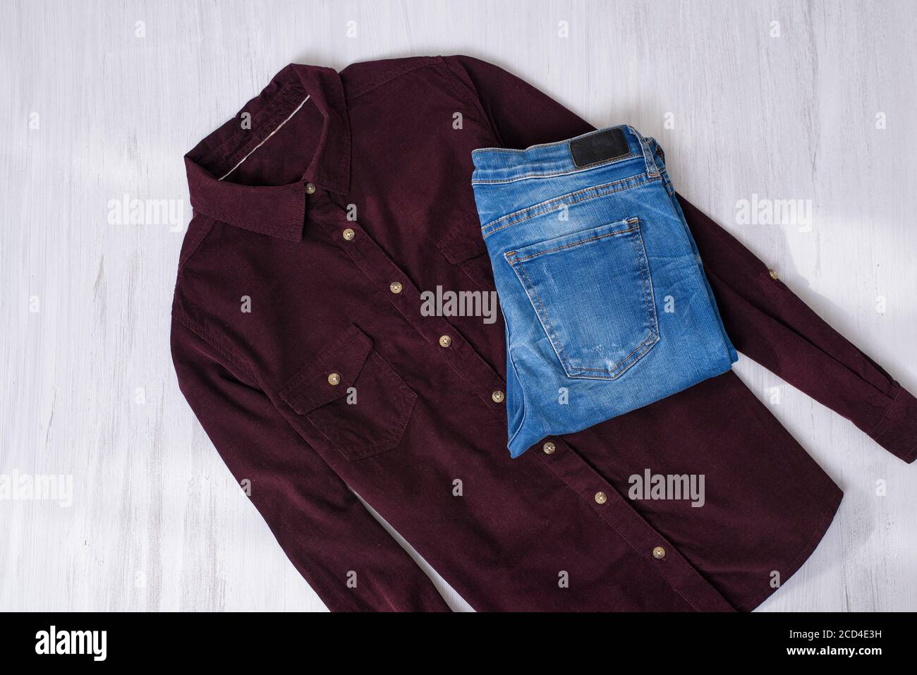 Maroon corduroy shirt and blue jeans on wooden background. Fashion concept  Stock Photo - Alamy