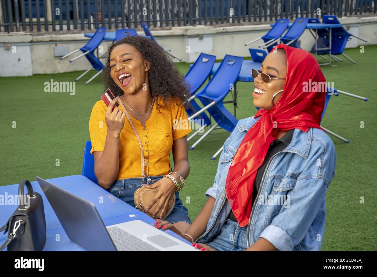 African females smiling and shopping online while sitting in a cafe Stock Photo