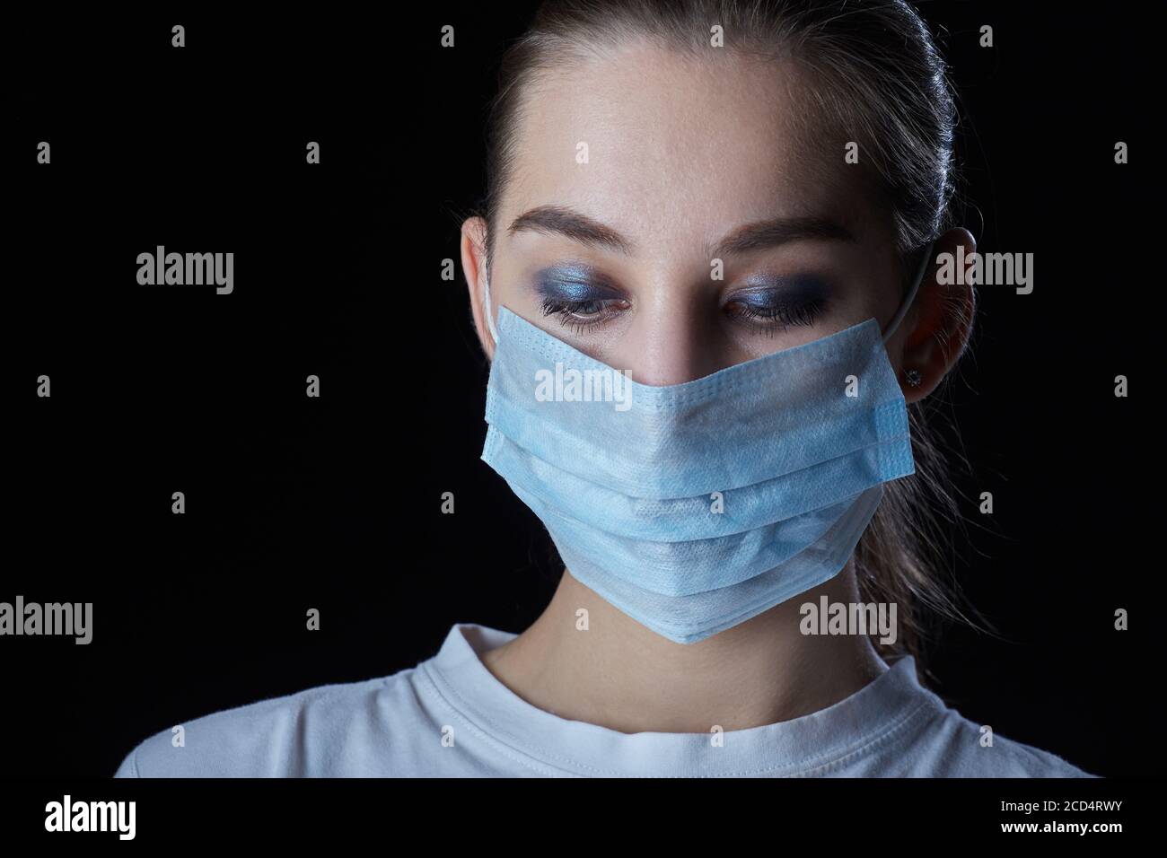 young sad woman in medical mask on black background looks down Stock ...
