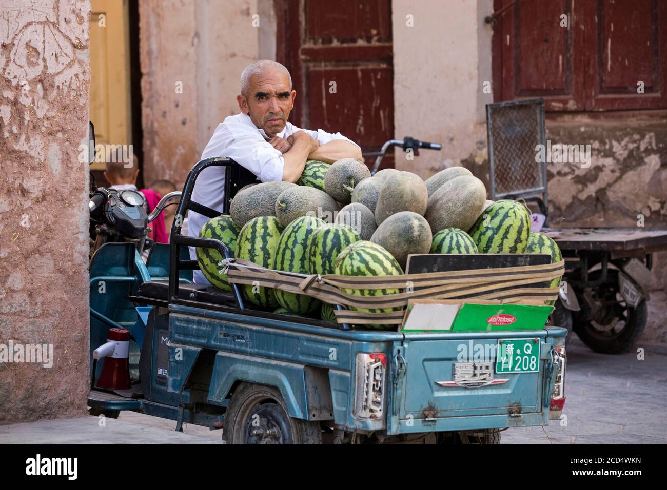 Uyghur street vendor selling watermelons in the city Kashgar / Kashi / Kasjgar, Xinjiang, China Stock Photo