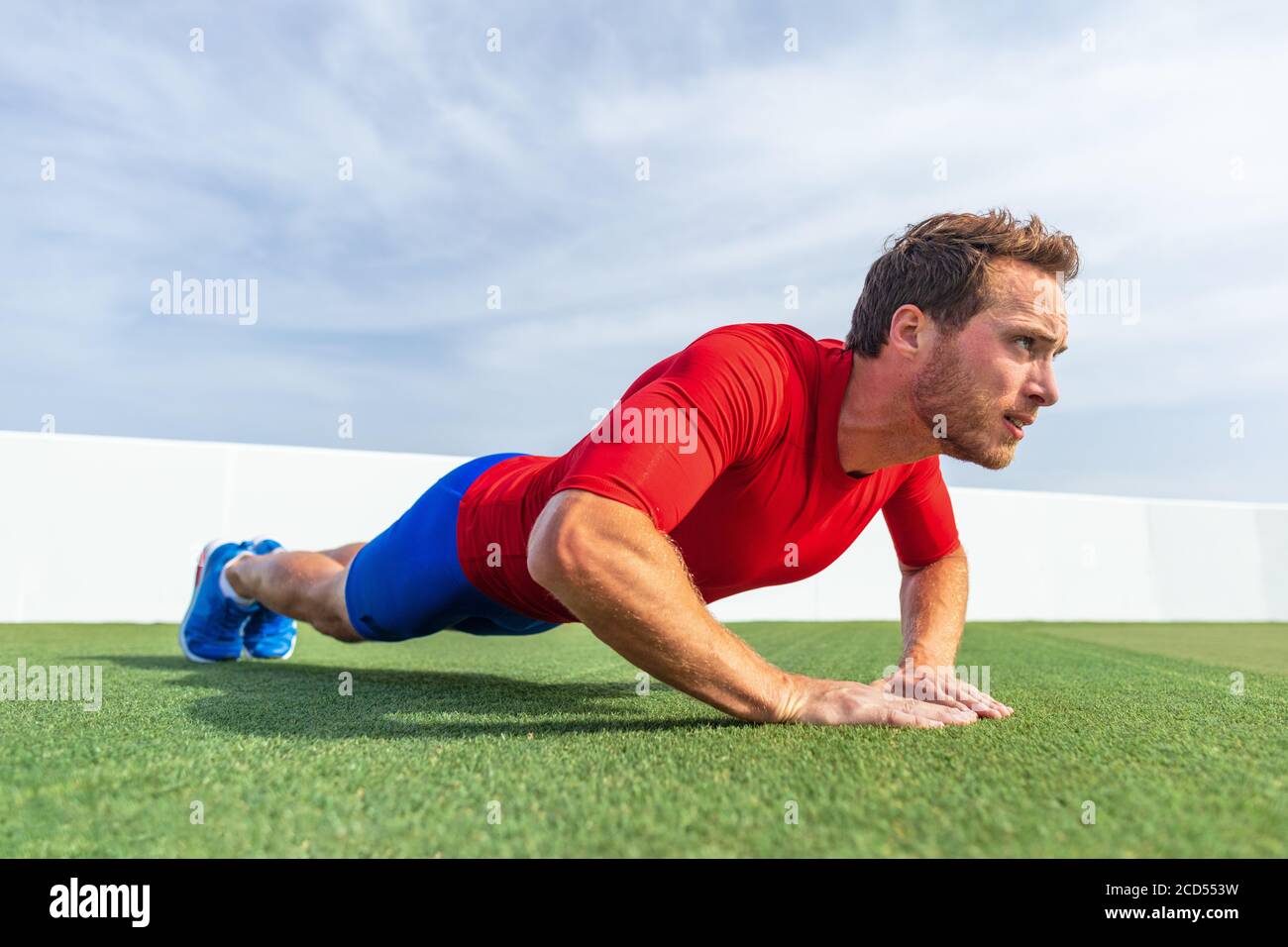 Fitness man doing diamond hand push ups exercises at outdoor grass park. Core body workout athlete planking or doing pushup Stock Photo