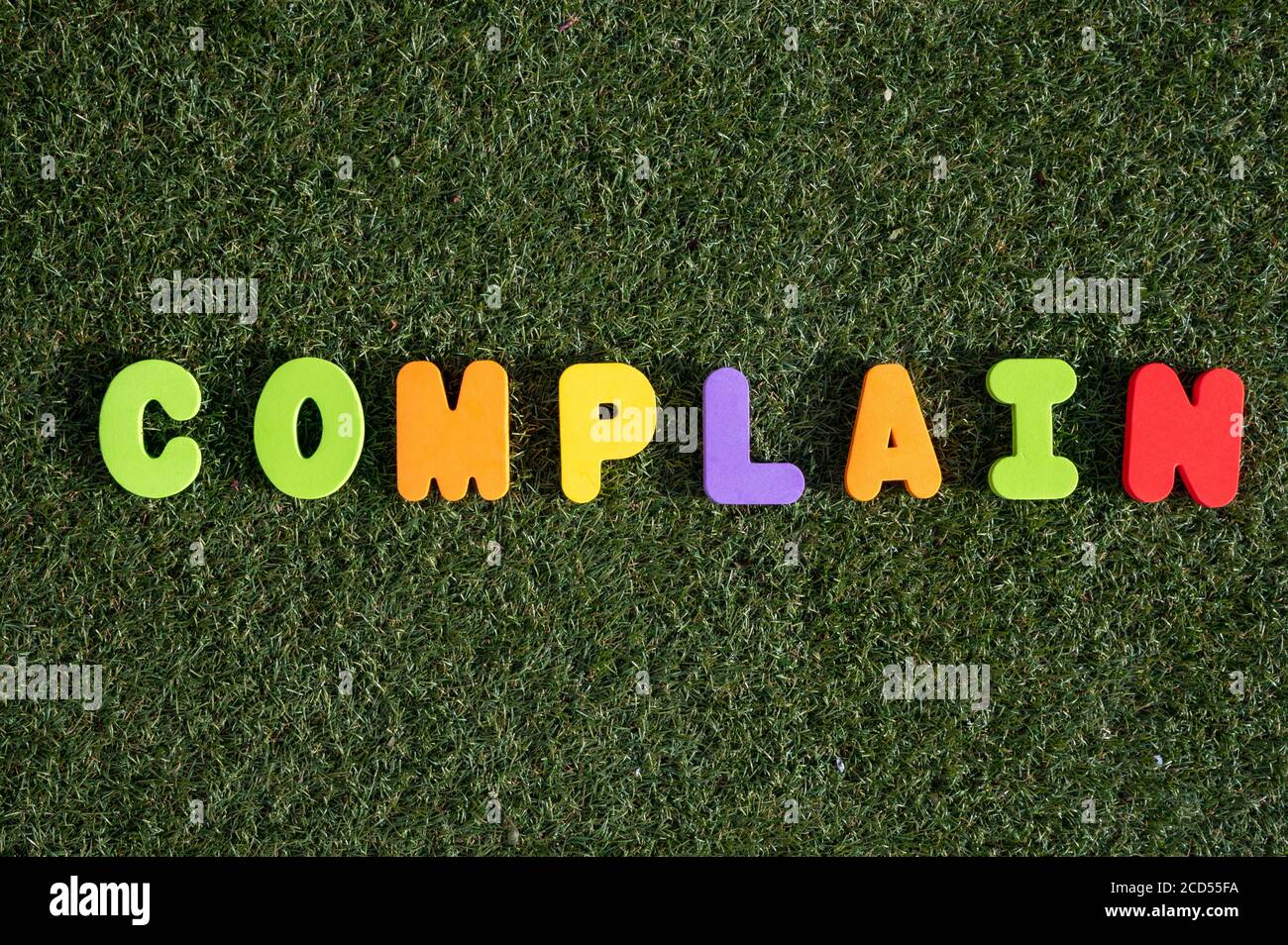 Capital letter 'Complain' word from colorful of wood on grass background. Stock Photo
