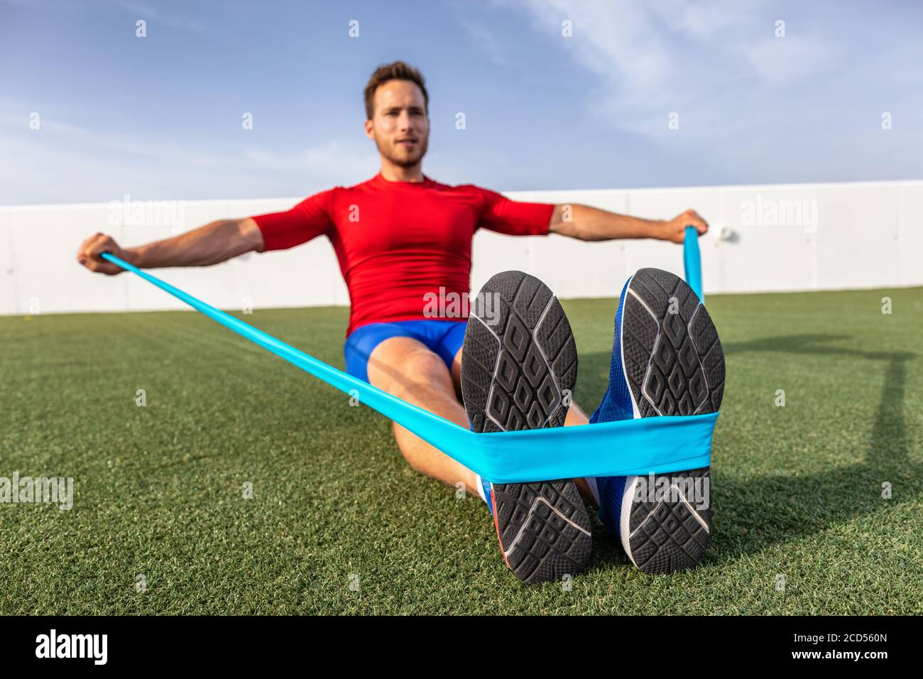 Fitness man training arms with resistance bands at outdoor gym or home garden. Body workout with equipment outside. Elastic rubber band accessory Stock Photo
