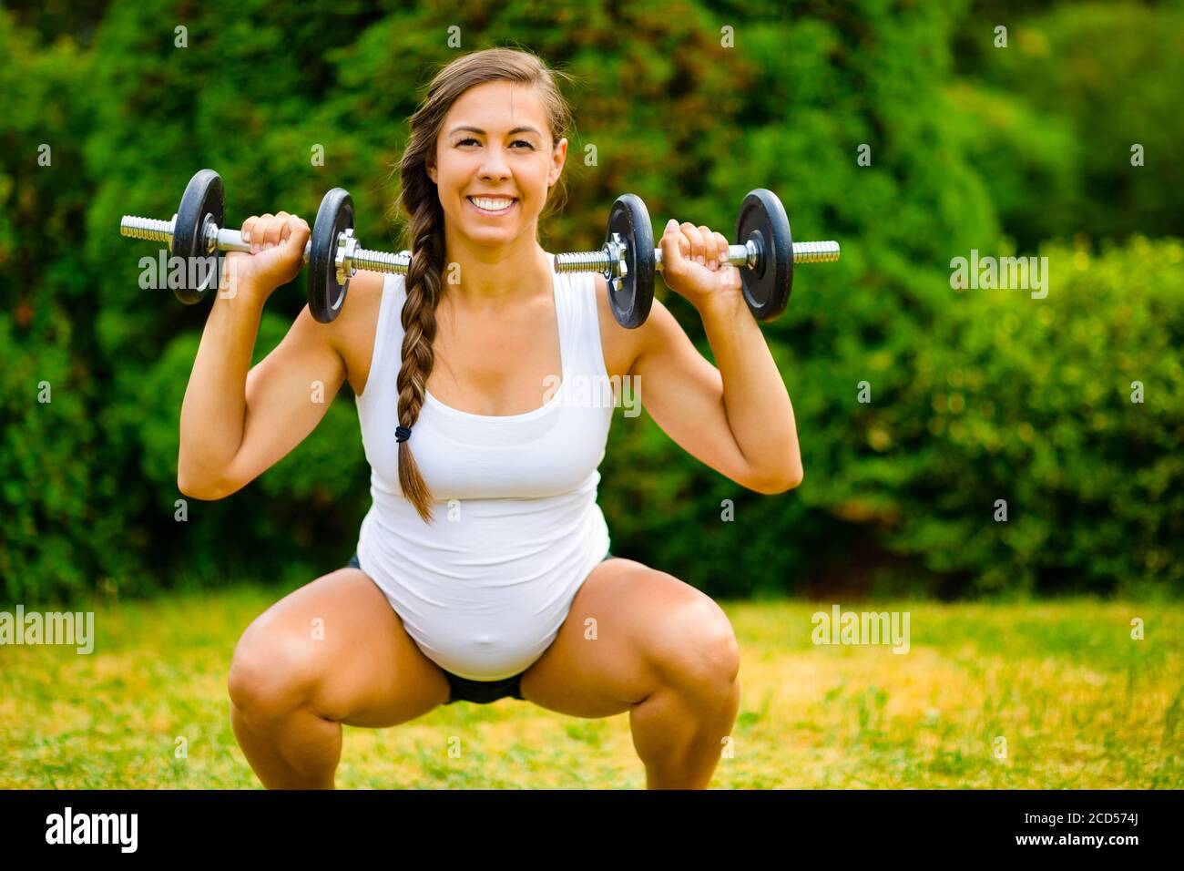 Smiling Pregnant Woman Doing Squat To Shoulder Press Using Dumbbells Stock Photo