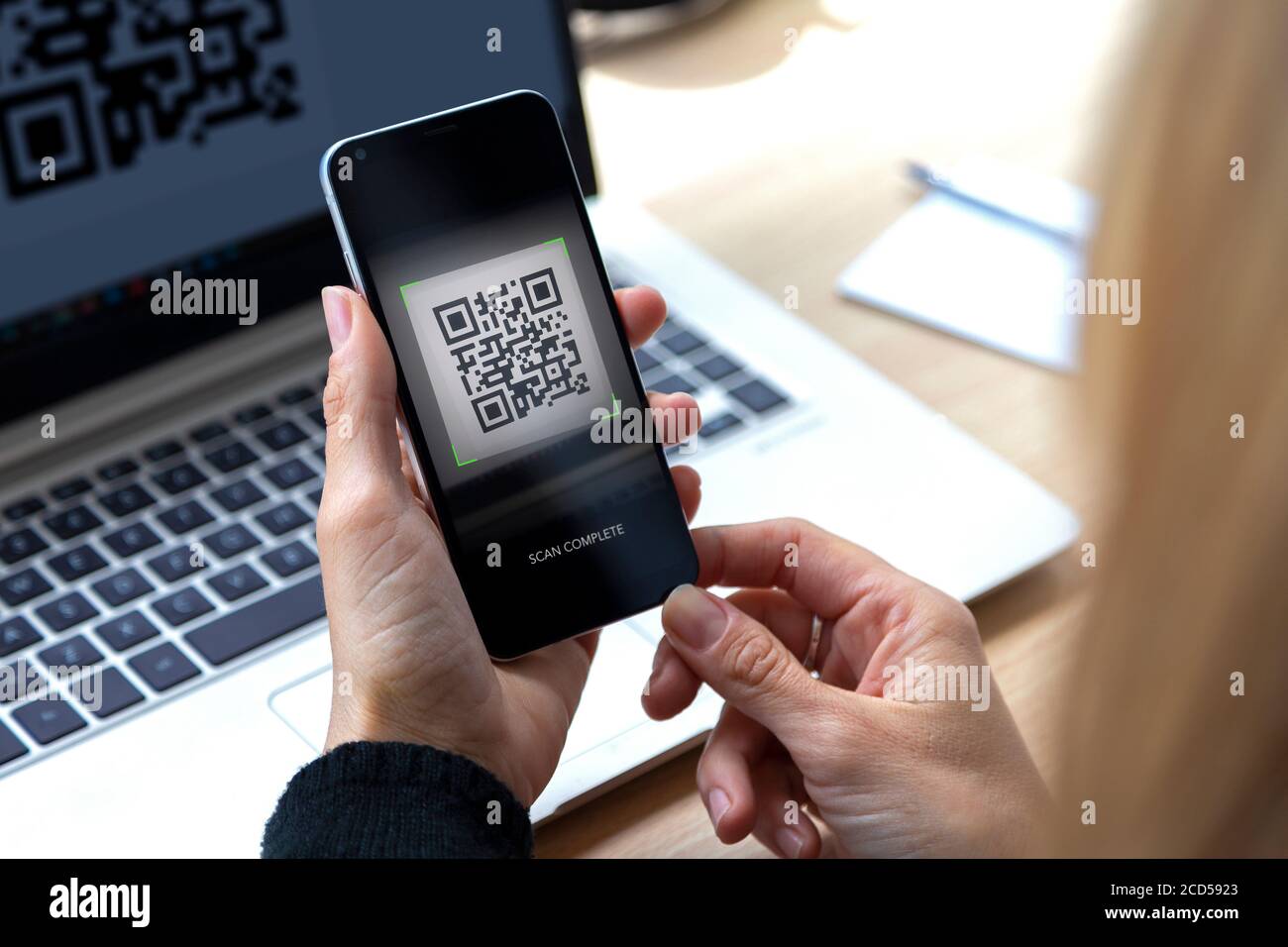 Woman with a cell phone in her hand scanning a QR code from the screen