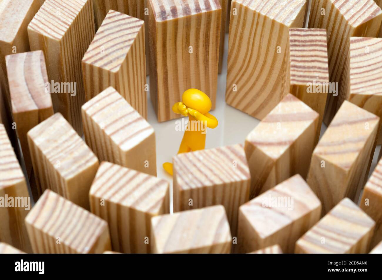 A human figure stands in the middle of high walls. Concept photo how high blockades limit the human being. Figure cries. Stock Photo