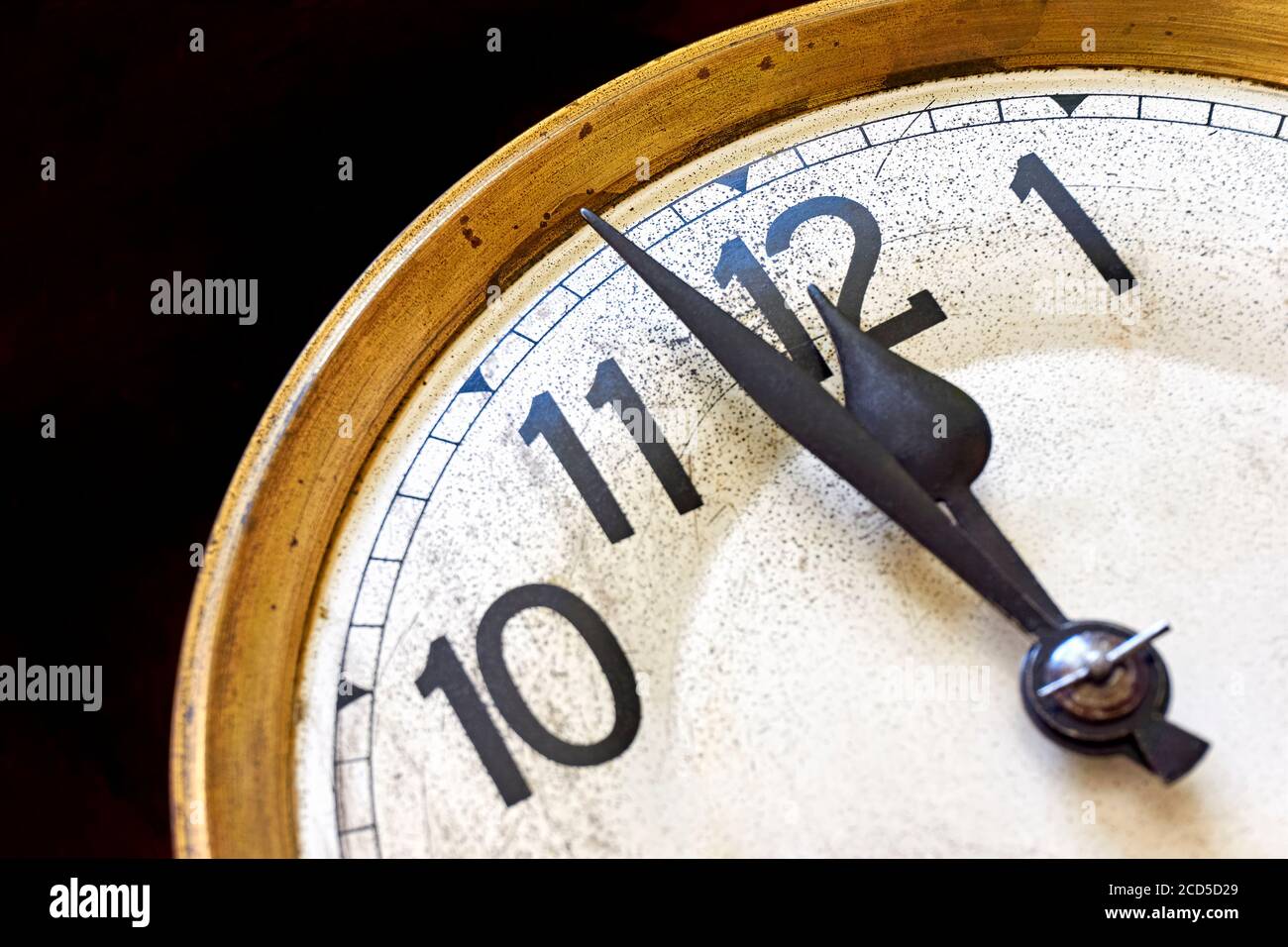 Old vintage clock shows 2 minutes to 12 o'clock against a black