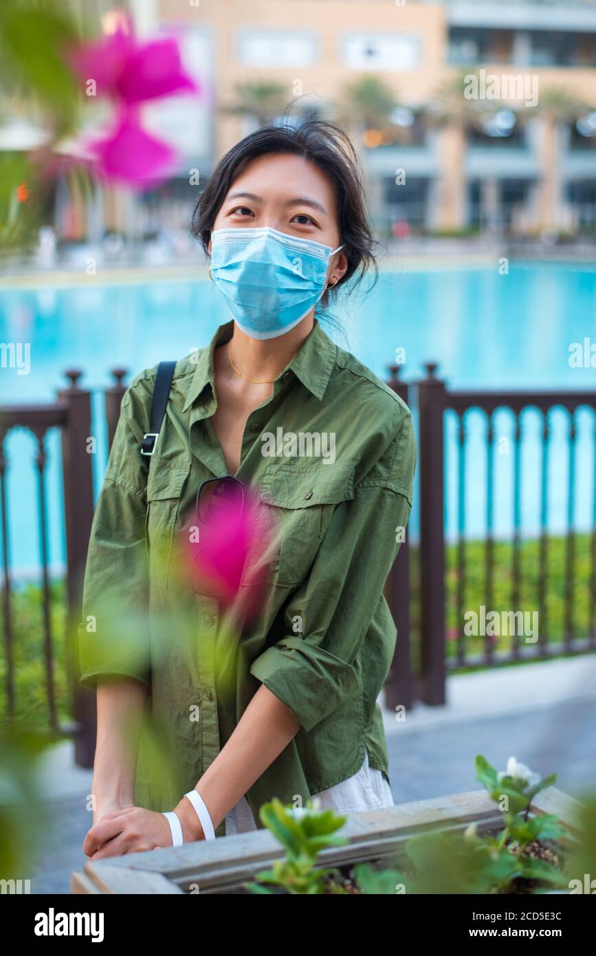 Asian woman wearing surgical face mask in outdoors area of a shopping mall in Dubai. Travel and leisure new normal after coronavirus Covid-19 pandemic Stock Photo