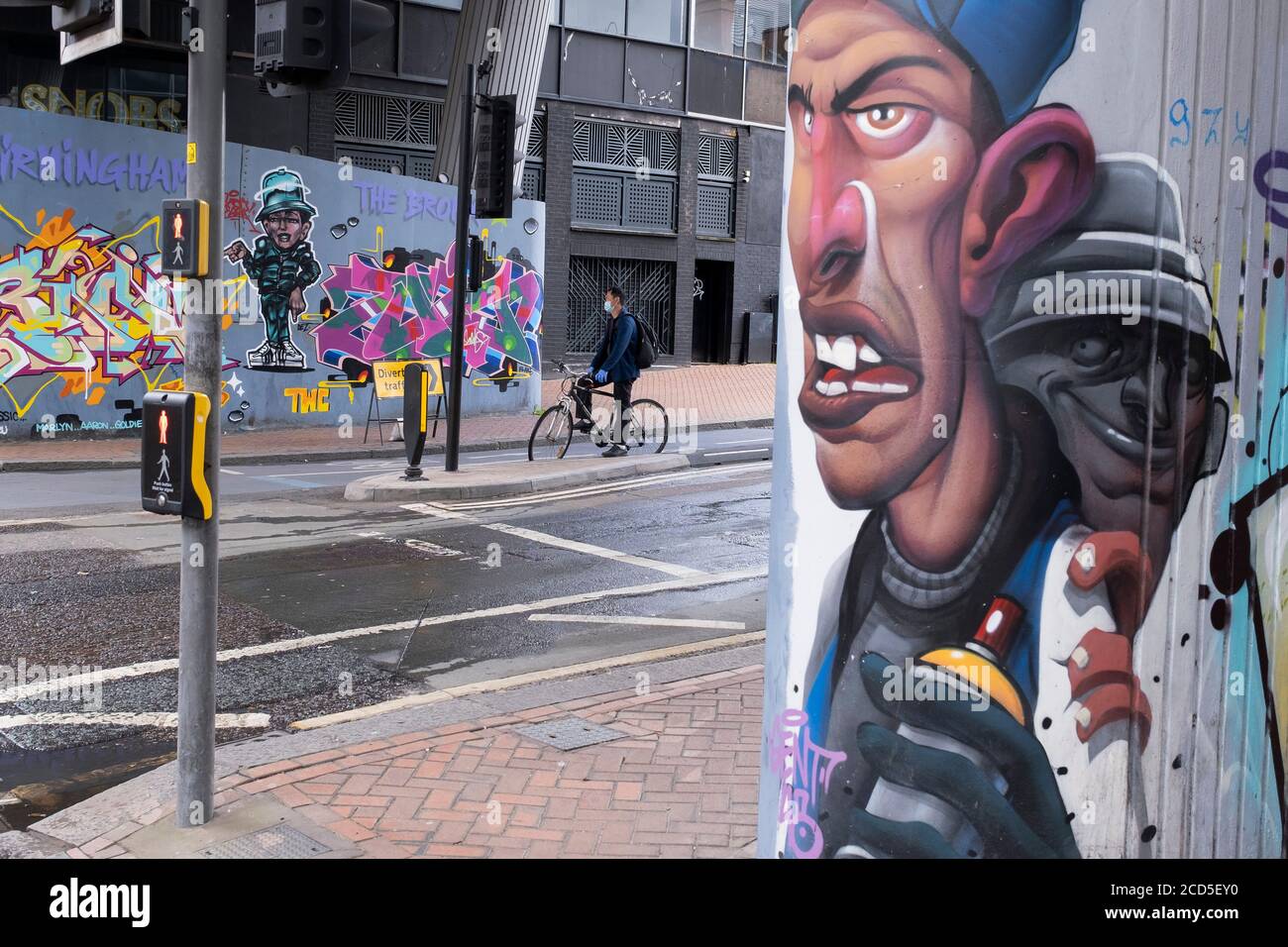 As numbers of Covid-19 cases in Birmingham have increased dramatically in recent weeks, and with the expectation that the city will be added to the watch list of critical areas which may face a local lockdown, people wearing face masks pass Birmingham street art graffiti in the city centre on 18th August 2020 in London, United Kingdom. With other areas in the Midlands under localised lockdown, people and businesses are being urged to follow the Coronavirus advice for workplace and family life help reduce the risk. Stock Photo