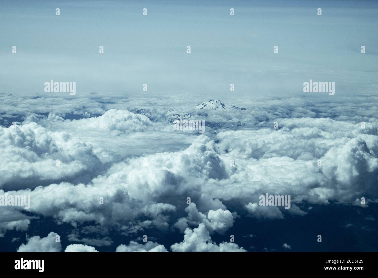 Aerial view of mountain peak rising above clouds Stock Photo