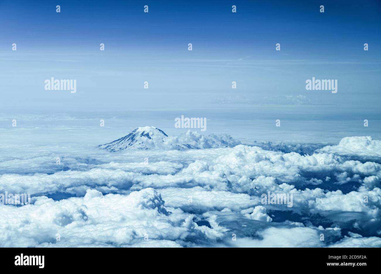 Aerial view of mountain peak rising above clouds Stock Photo