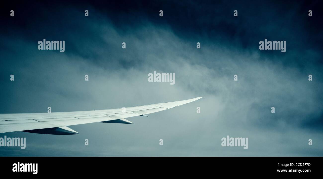 Photograph of airplane wing with clouds in background Stock Photo