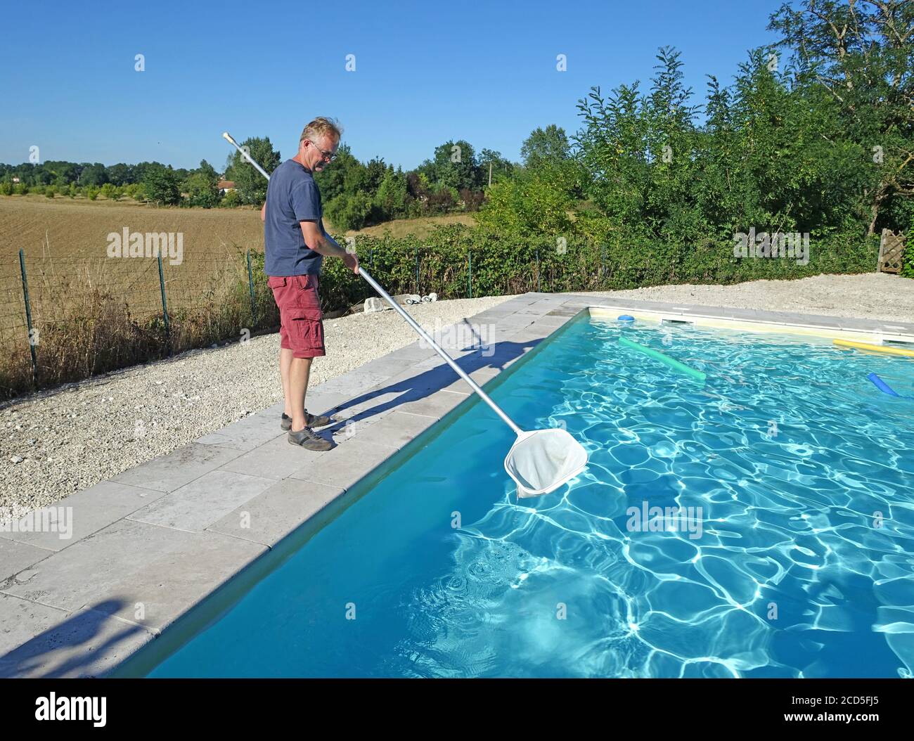 man cleaning a swimming pool with a net Stock Photo