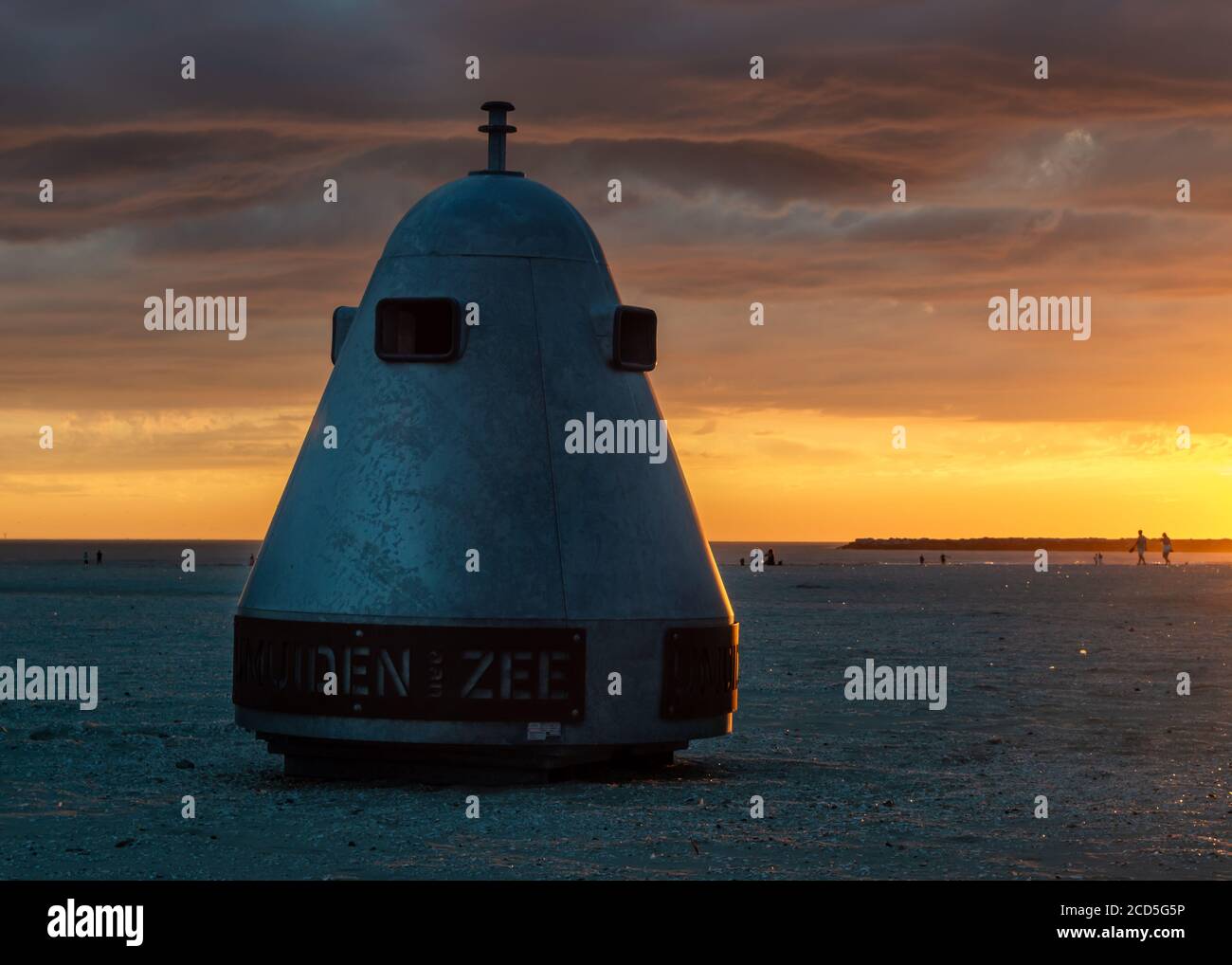 Beach garbage can and people enjoying the sunset. Text translation: Ijmuiden at sea Stock Photo