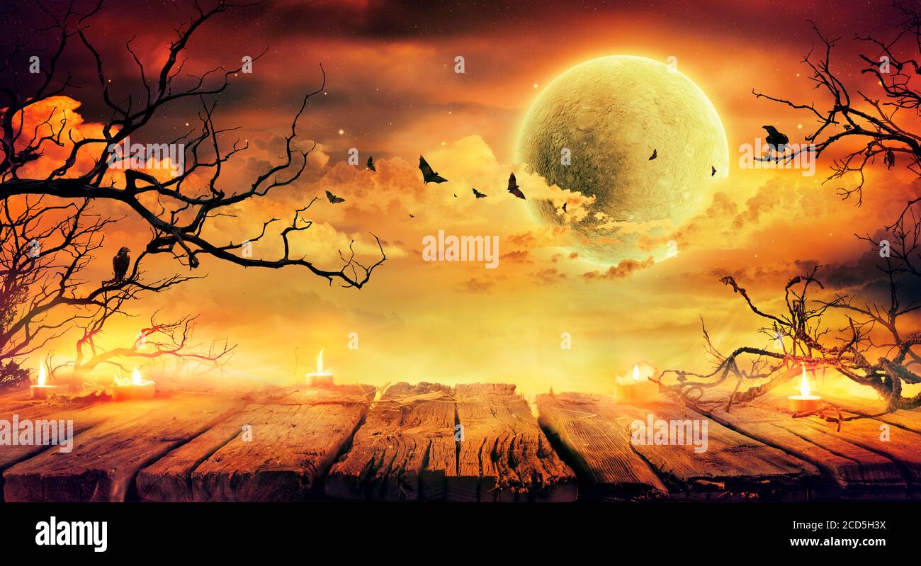 Halloween In Orange - Old Table With Candles And Branches At Scary Night With Full Moon Stock Photo