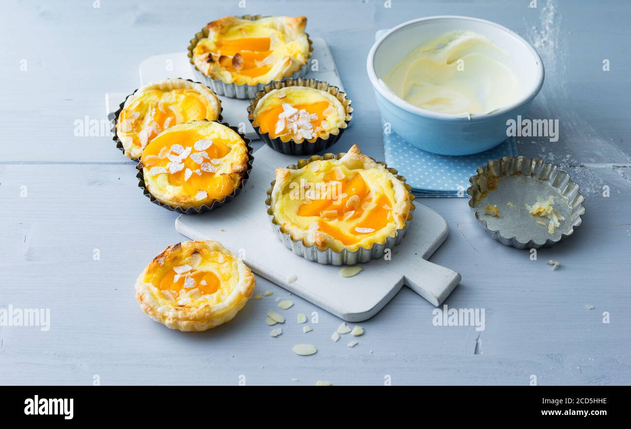 Peach tartlets with sour cream in the baking pan on cutting board Stock Photo