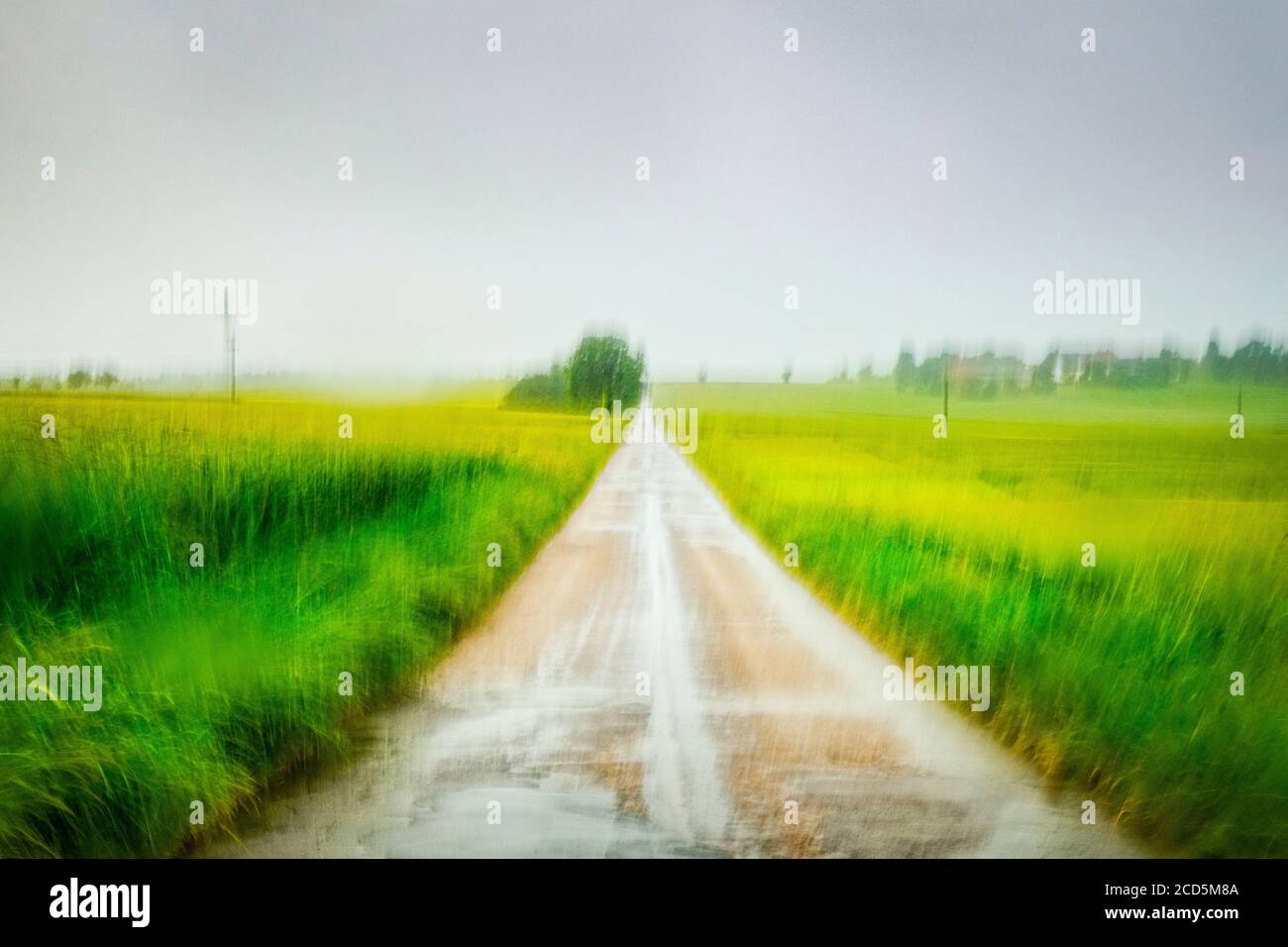 View of fields and country road under overcast sky Stock Photo