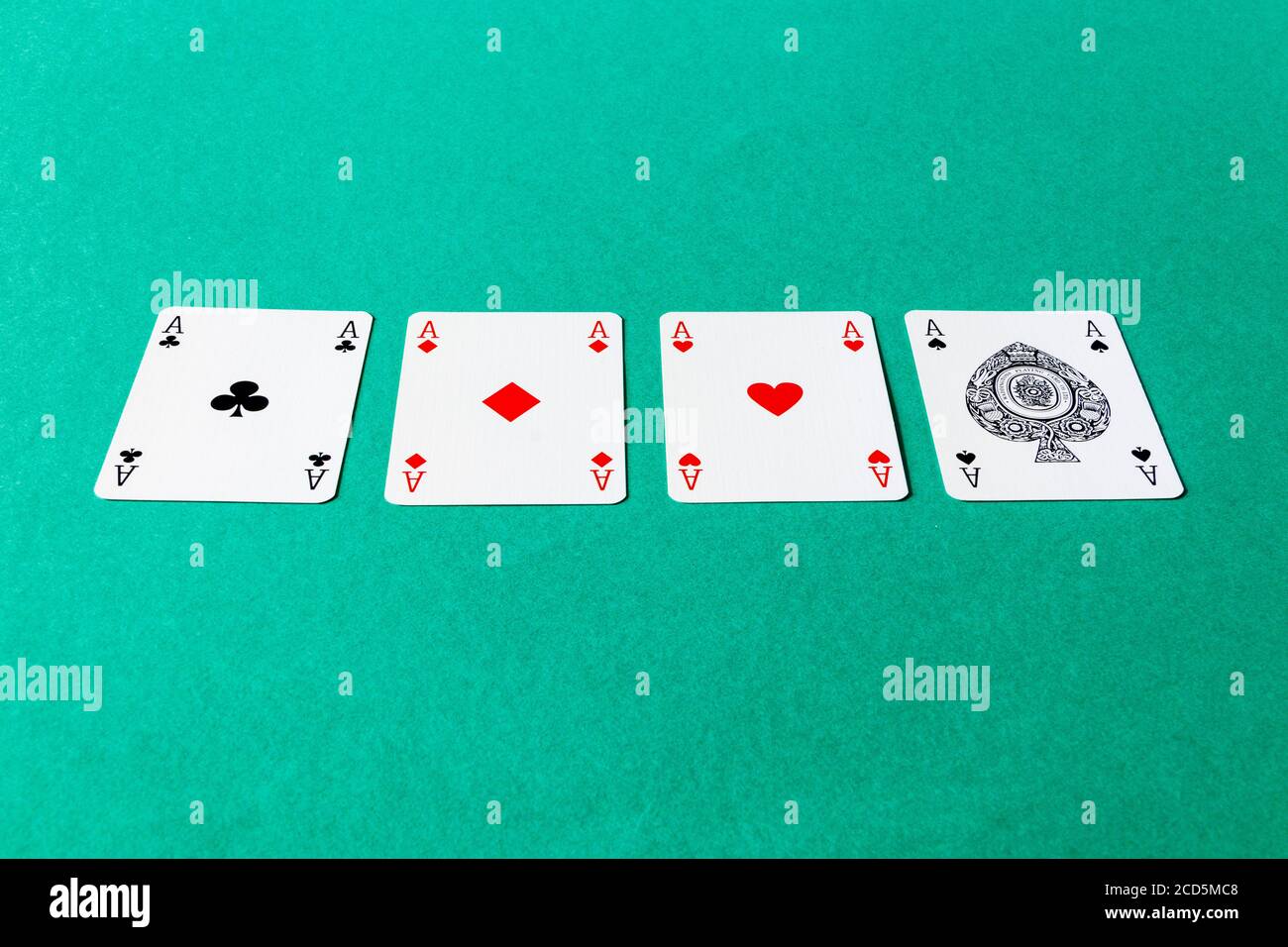 The four aces from a pack of cards lined up on a card table Stock Photo