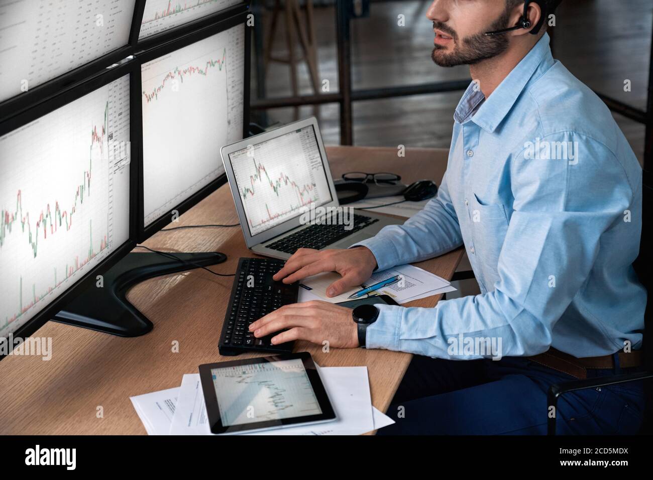 Trader in headset analyzing stat and dynamic on forex charts Stock Photo