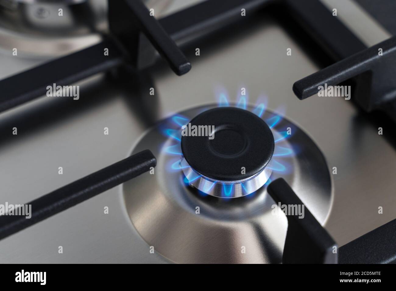 Closeup blue flame from a gas stove burner. Stainless steel kitchen surface  with cast-iron grill Stock Photo - Alamy