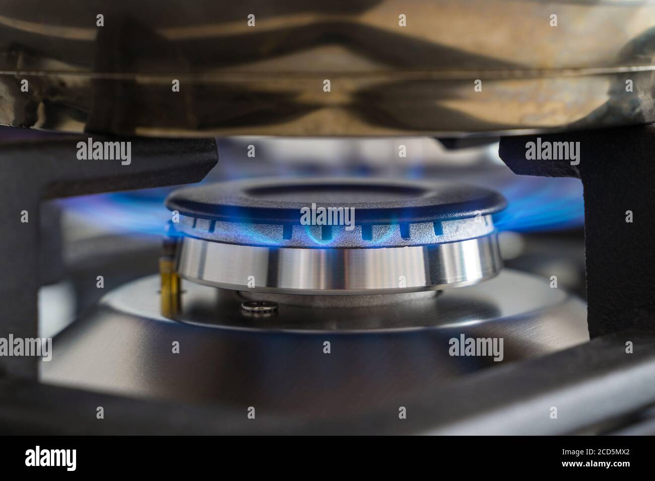 Closeup blue flame from a gas stove burner. Stainless steel kitchen ...