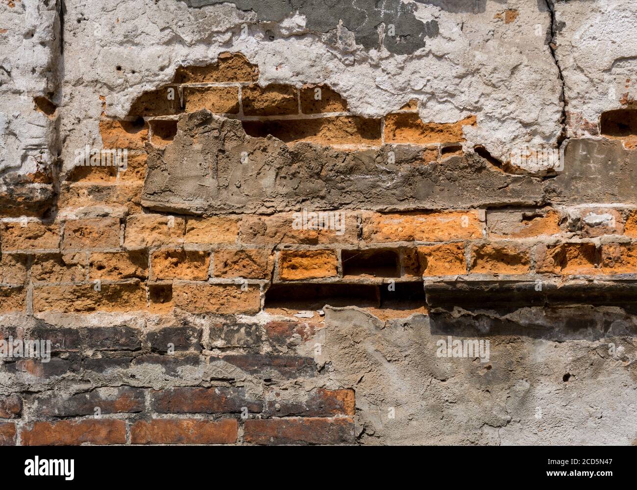 Dilapidated with potholes old brick wall of the building, made of red