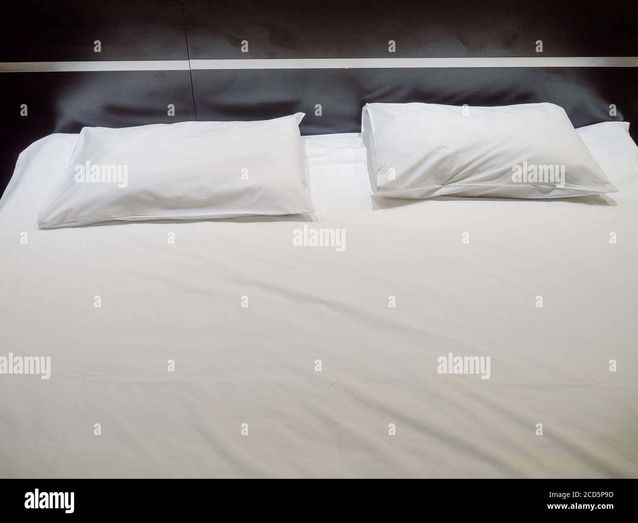 Two rectangular pillows in white pillowcases lie on a white sheet Stock Photo