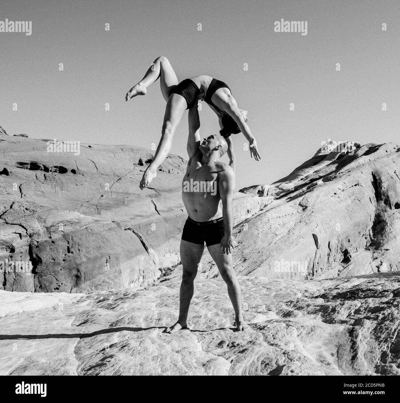 Balancing pair of gymnasts in desert,  State Park, Overton, Nevada, USA Stock Photo