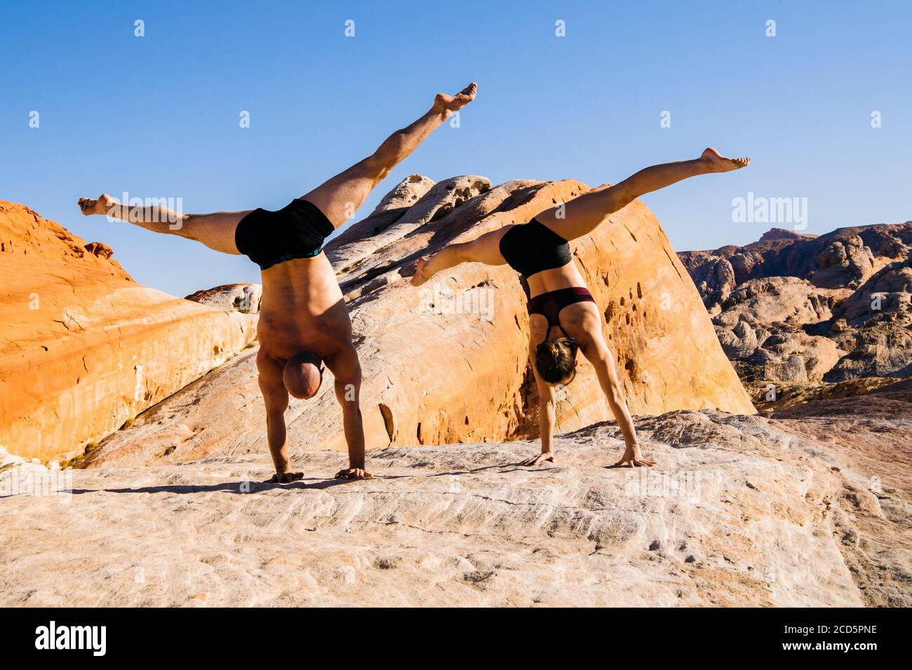 Two gymnasts doing handstands in desert,  State Park, Overton, Nevada, USA Stock Photo