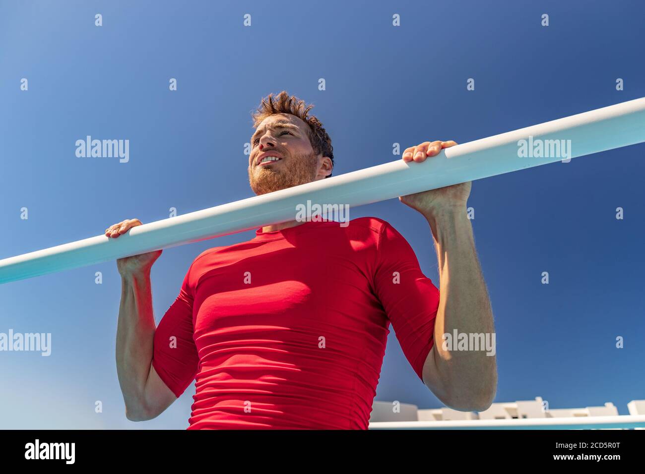 Fit man training arched back pull up on bar gym workout shoulder exercise. Male athlete working out outside Stock Photo