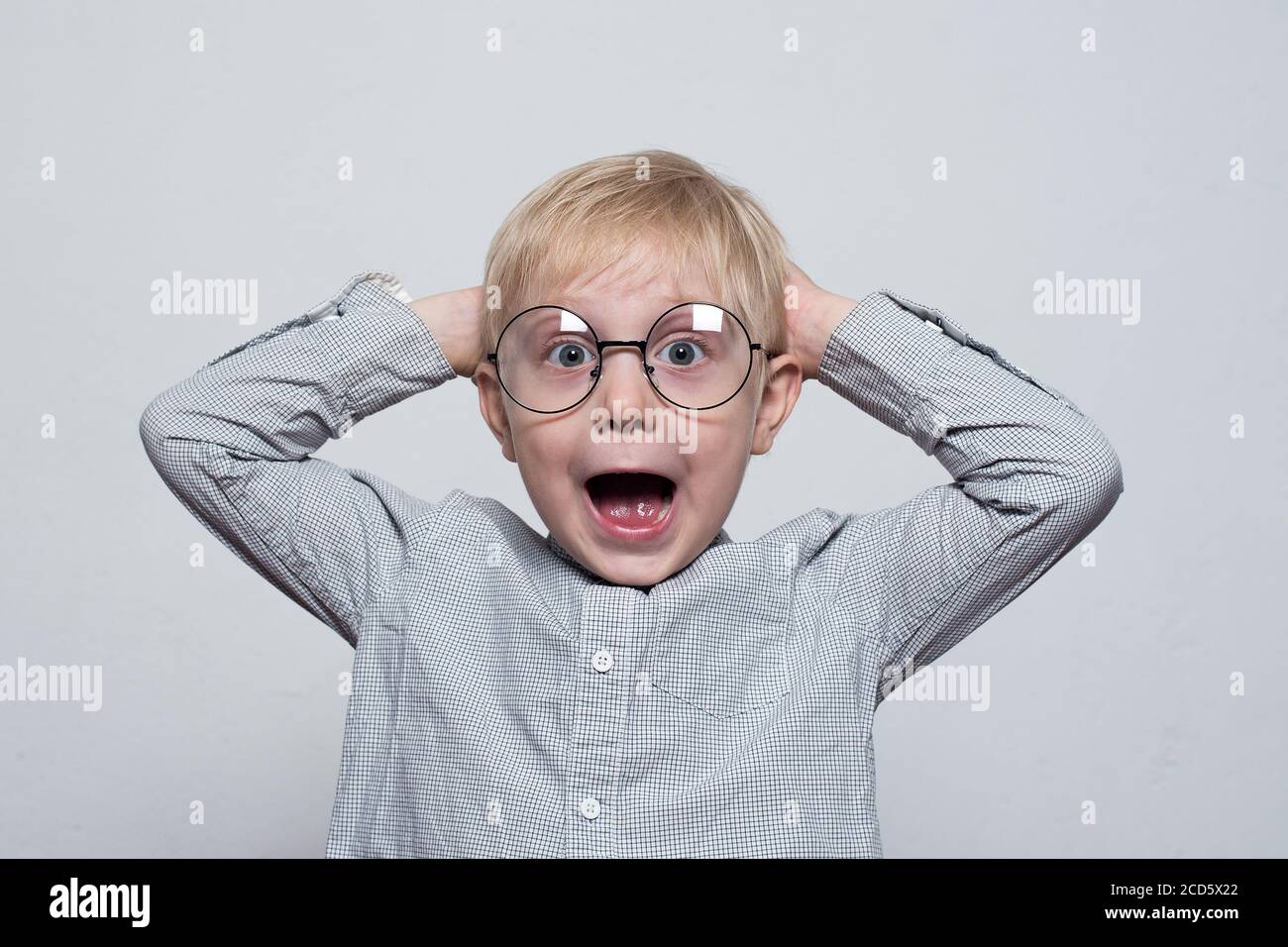 Cheerful blond boy in glasses holding hands behind his head. Half