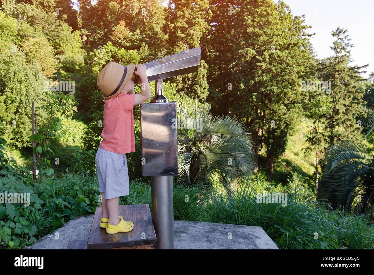 Little boy looking through telescope for tourists on observation deck ...